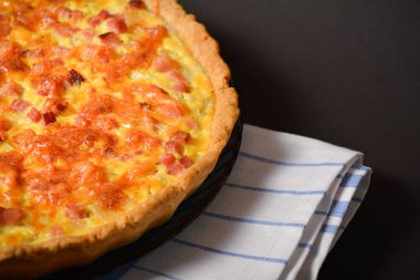 Pastırma, soğan ve tavuk yumurtalı Fransız kiş Lorraine 'inin bir parçası. Mutfak havlusunda servis edilen kremalı hamur. Klasik tarif işte. Alman turtası. Siyah arkaplan.