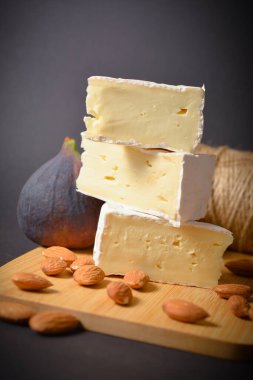 Yumuşak peynirli, incir meyveli ve bademli sağlıklı bir peynir tahtası. Üç parça beyaz küflü Fransız peyniri, meyveli, fındıklı ve siyah zemin üzümlü. Boşluk resmini kopyala