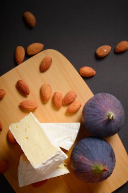 Krem peynirli krem peynirin en üst görüntüsü. Yumuşak peynirli peynir tahtası. Tahtada badem fıstığı ve incir meyveleriyle servis edilen tabaklar. Beyaz yumuşak peynir. Aperatifler ve başlangıçlar.