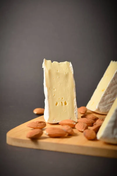 侧视图的奶酪板与软法国Brie奶酪块与杏仁坚果在木板上的深色背景 三块芝士和杏仁开胃菜 开胃菜 — 图库照片