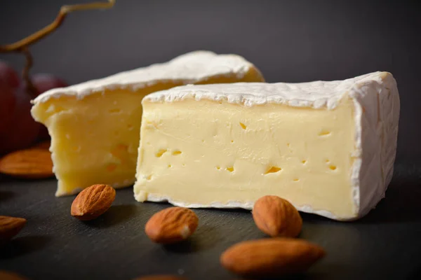关闭了法国霉菌奶酪Brie碎片 奶酪板与软奶酪片 Platter与杏仁坚果一起在黑色背景下食用 白色软奶酪 开胃菜和开胃菜 — 图库照片