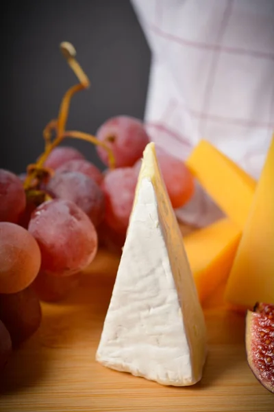 用硬的和软的法国奶酪 粉红的葡萄和一些无花果做成的美味的健康的奶酪板 白模奶酪 水果切碎 黑底葡萄 厨房毛巾 — 图库照片