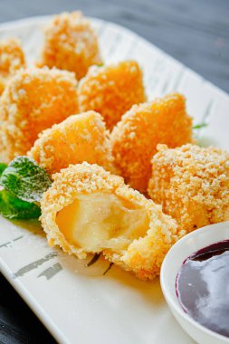 Böğürtlen soslu kızarmış peynir, taze nane yaprakları, beyaz tabakta pudra şekeri. Kızarmış peynirli peynirli peynirli tost ekmeği.