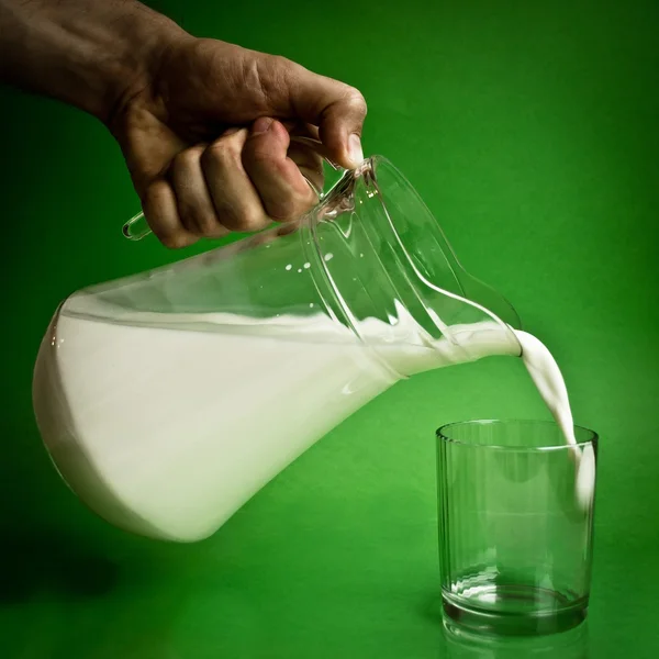 Verter leche de una jarra en un vaso — Foto de Stock