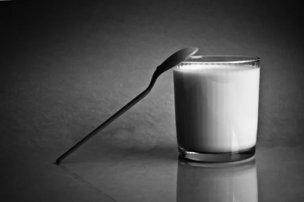 El vaso de leche y basado en su cuchara — Foto de Stock