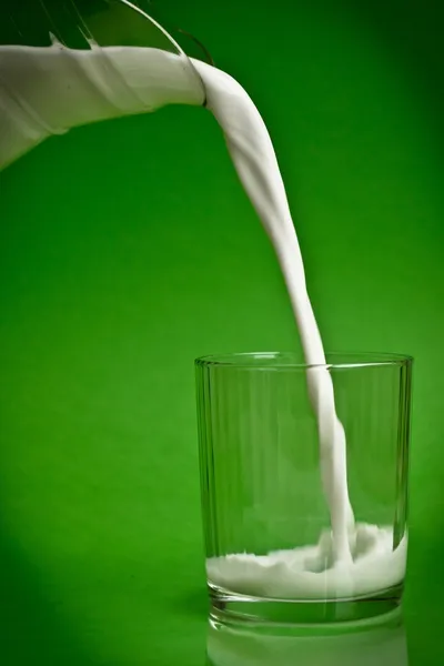 Milch aus einem Krug in ein Glas gießen — Stockfoto