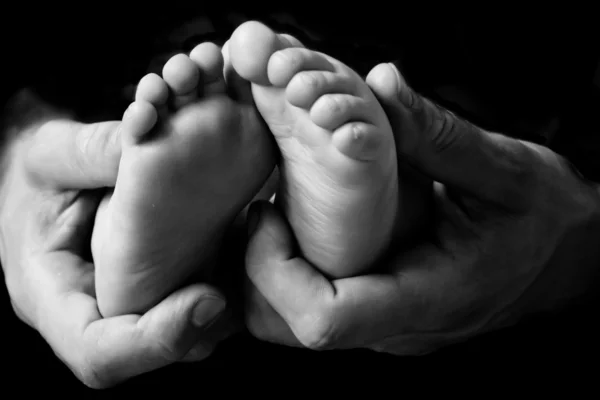 Petits pieds de bébé tenus par les mains des hommes — Photo