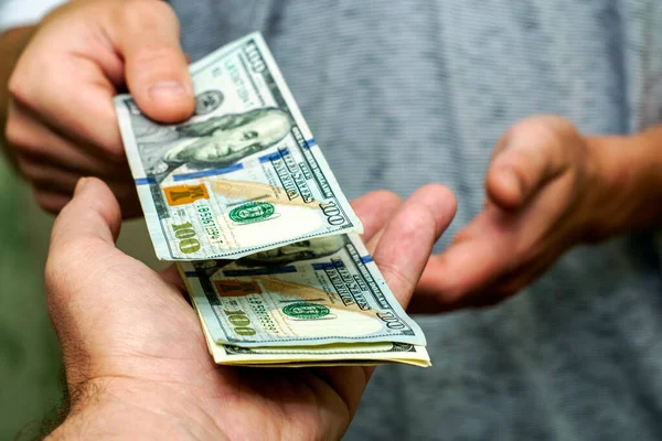 Bir kişi, bir diğerinin yanından yüz dolarlık banknotları sayarak geçer. Yüksek kalite fotoğraf