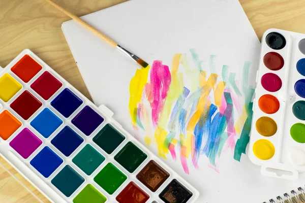 Akvarel maluje štětec a bílý list se vzorky barev na stole Stock Fotografie