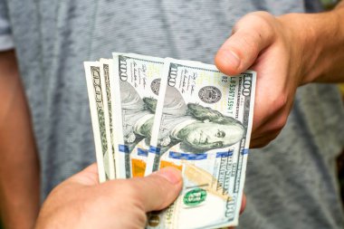 Biri 100 dolarlık banknotları diğerine uzatıyor. Yüksek kalite fotoğraf