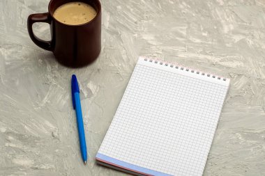 Bir fincan kapuçino kahve bir not defteri ve gri bir yüzeyde dolmakalem. Yüksek kalite fotoğraf