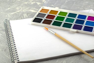 suluboya boya fırça ve eskiz defterini gri-beyaz bir yüzeye çizmek için kullanır. Yüksek kalite fotoğraf