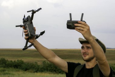 Şapkalı genç bir turist elinde bir kuadkopter ve uzaktan kumanda tutuyor. Yüksek kalite fotoğraf