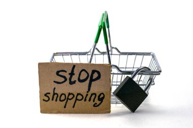 Makul tüketimi satın almayı reddetme kavramı, üzerinde asma kilit ve beyaz arka planda alışveriş yapmayın yazan bir tabela olan bir alışveriş sepetidir. Yüksek kalite fotoğraf