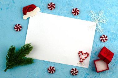 Yeşil köknar dalları tarafından çerçevelenmiş mavi bir yüzeyde beyaz bir çarşaf hediye kutuları dolusu lolipoplar ve kar taneleri Noel Baba 'ya Noel Baba' nın yeni yıl dileklerini içeren kavramsal bir mektuptur. Yüksek kalite fotoğraf