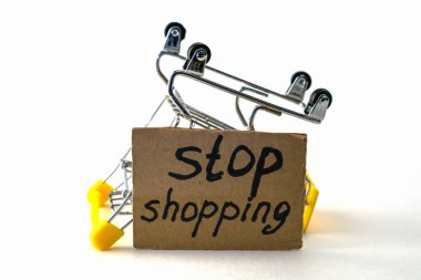 Makul tüketimi satın almayı reddetme kavramı, beyaz arka planda, alışveriş yapmayı bırak yazan bir tabelanın yanında ters dönmüş bir alışveriş arabasıdır. Yüksek kalite fotoğraf