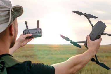 Şapkalı genç bir turist elinde bir kuadkopter ve uzaktan kumanda tutuyor. Yüksek kalite fotoğraf