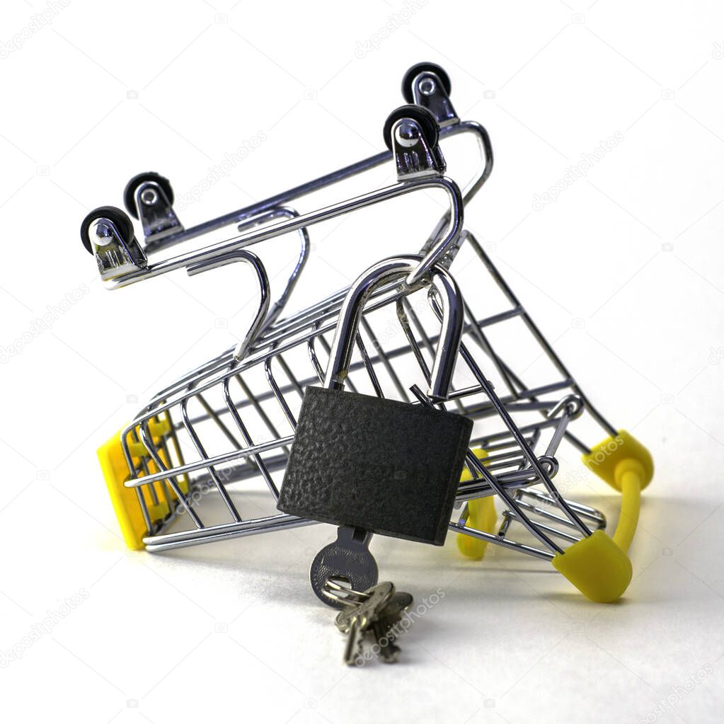 the concept of abandoning the purchase of reasonable consumption is an inverted shopping cart with a padlock on a white background. High quality photo