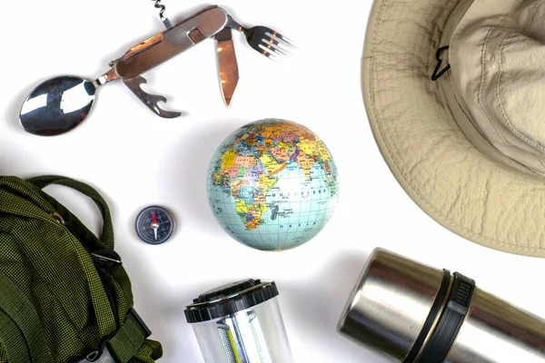 トラベルバックパックコンパス地球折りたたみ旅行刃物テントランタン魔法瓶と帽子白い表面に 高品質の写真 — ストック写真