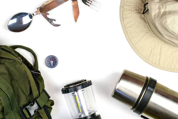 Cestovní batoh kompas skládací cestovní příbory stan lucerna termoska a klobouk na bílém povrchu copyspace Stock Snímky