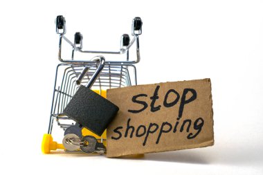 Makul tüketimi satın almayı reddetme kavramı, üzerinde asma kilit olan ters dönmüş bir alışveriş arabası ve beyaz arka planda alışveriş yapmayı durduran bir levhadır. Yüksek kalite fotoğraf