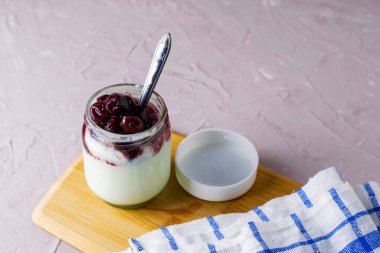 Havlunun yanında kiraz reçelli yoğurt kavanozu. Yüksek kalite fotoğraf