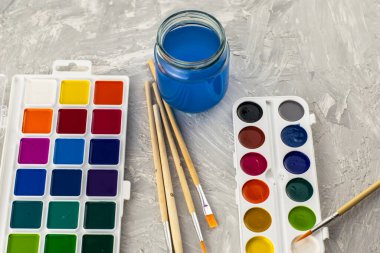 Suluboya fırça ve gri bir yüzey üzerinde bir kavanoz su. Yüksek kalite fotoğraf