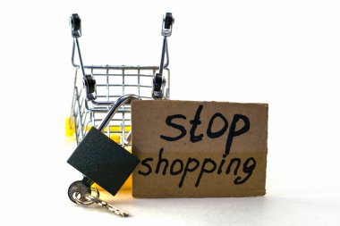 Makul tüketimi satın almayı reddetme kavramı, üzerinde asma kilit olan ters dönmüş bir alışveriş arabası ve beyaz arka planda alışveriş yapmayı durduran bir levhadır. Yüksek kalite fotoğraf