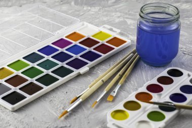 Suluboya fırça ve gri bir yüzey üzerinde bir kavanoz su. Yüksek kalite fotoğraf