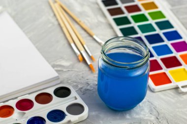 Suluboya fırça ve gri bir yüzey üzerinde bir kavanoz su. Yüksek kalite fotoğraf