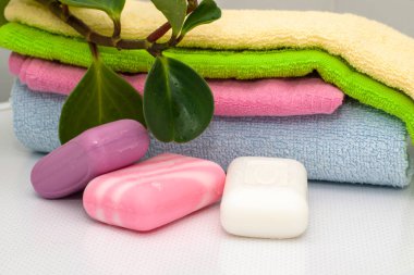 Bir yığın havlu üç kalıp sabun ve tuvalet masasında bir saksı çiçeği. Yüksek kalite fotoğraf