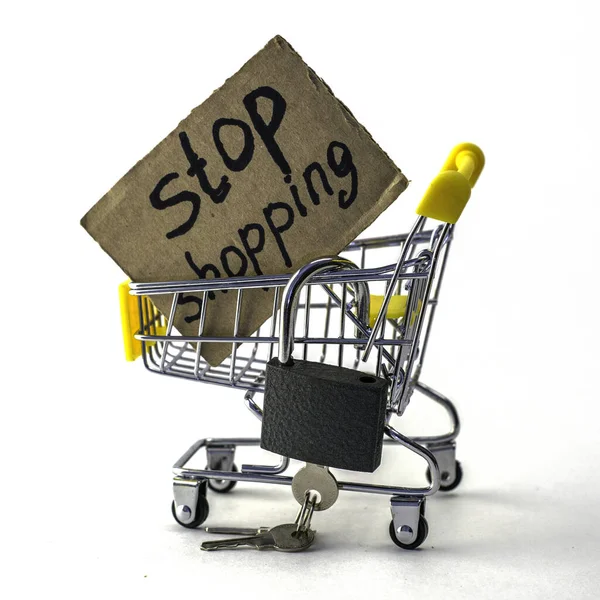 the concept of refusing to buy a reasonable consumption shopping cart with a padlock and a sign saying stop shopping on a white background. High quality photo