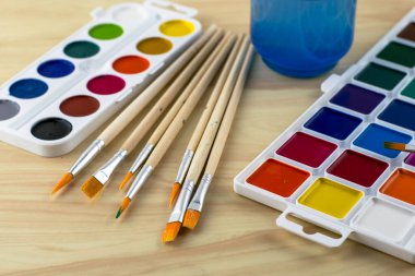 Suluboya fırçalar ve masanın üstünde bir kavanoz su. Yüksek kalite fotoğraf