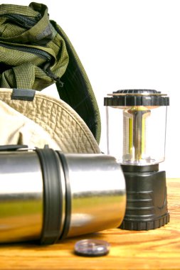 Turist sırt çantası termos pusula fener ve beyaz arka planda ahşap zemin üzerinde şapka. Yüksek kalite fotoğraf