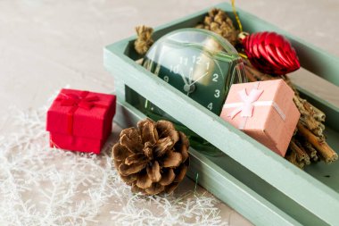 Noel süslemeleri ve saatleri olan ahşap bir kutunun arkasında bir çam kozalağı ve hediye kutusu. Yüksek kalite fotoğraf