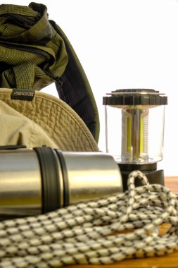 Turist sırt çantası termosu halat fenere tırmanıyor ve beyaz zemin üzerinde ahşap bir şapka takıyor.