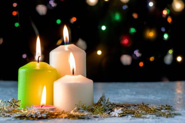 Siyah Noel arkaplanı renkli ışıklar yanan mumlar ve ön planda dekoratif kar taneleri. Yüksek kalite fotoğraf
