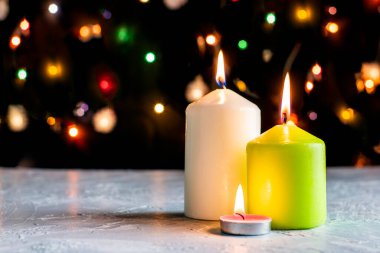 Siyah Noel arka planında renkli ışıklar ve ön planda yanan mumlar var. Yüksek kalite fotoğraf