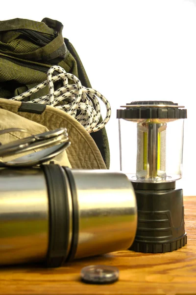 Turist sırt çantası termos tırmanma halatı pusula katlama fener ve beyaz arka planda ahşap zemin üzerinde şapka. Yüksek kalite fotoğraf