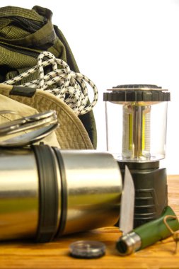 Turist sırt çantası termos tırmanma halatı pusula katlanır bıçak fener ve beyaz arka planda ahşap zemin üzerinde şapka. Yüksek kalite fotoğraf