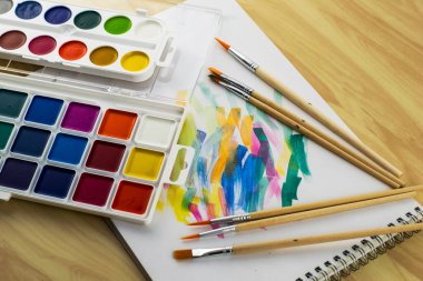 Renk örnekleriyle dolu beyaz bir çarşafta suluboya boyalar ve fırçalar. Yüksek kalite fotoğraf