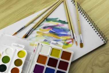 Renk örnekleriyle dolu beyaz bir çarşafta suluboya boyalar ve fırçalar. Yüksek kalite fotoğraf