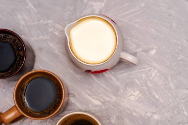 Masanın üstünde bir sürahi süt ve üç kupa kahve var. Yüksek kalite fotoğraf