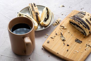 Bir fincan kahve ve içinde haşhaş tohumları ve çikolata olan dilimlenmiş börek. Yüksek kalite fotoğraf