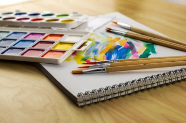 Renk örnekleriyle dolu beyaz bir çarşafta suluboya boyalar ve fırçalar. Yüksek kalite fotoğraf