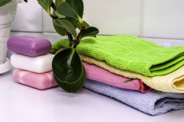 Bir yığın havlu, sabun ve banyo masasının üzerinde bir saksı.