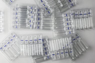 Beyaz arka planda cam ampulleri olan şeffaf plastik kaplar.