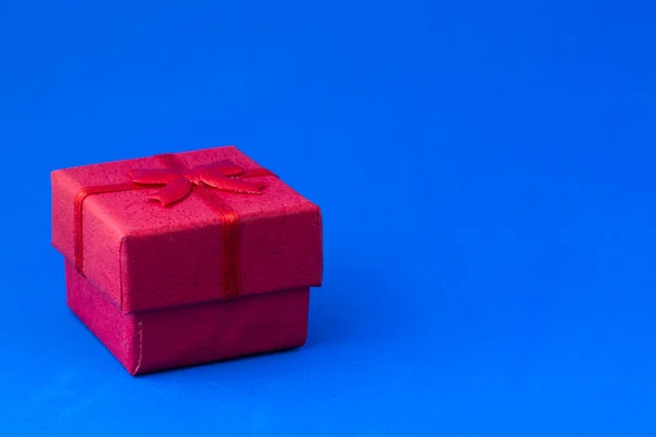 Caja de regalo roja sobre un fondo azul con copyspace — Foto de Stock