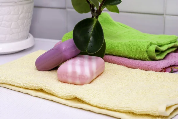 A stack of towels bars of soap and a houseplant on the bathroom table — Stock Photo, Image