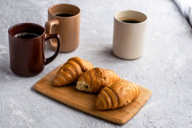Masada üç kupa kahve ve kruvasan var. Yüksek kalite fotoğraf
